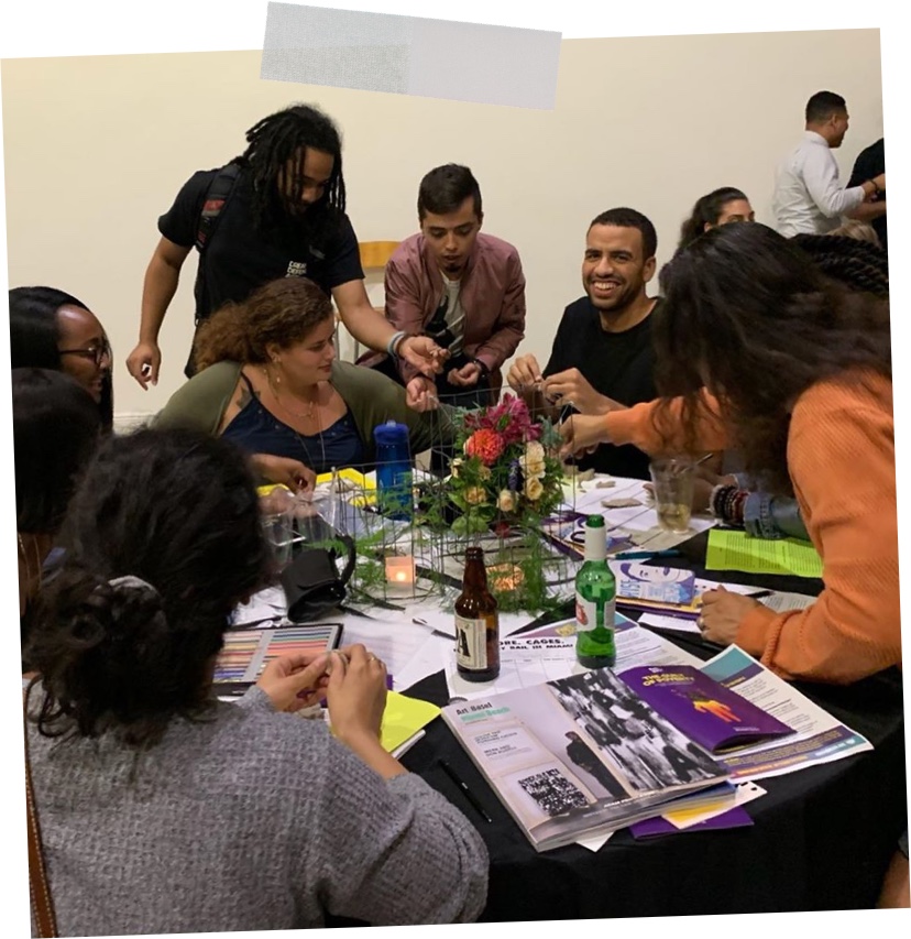 free-the-block-table A group of smiling people sitting a table doing radical crafts